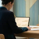 Une femme d'affaires consulte des graphiques financiers sur une tablette dans un bureau moderne.