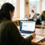 Personne vue de dos suivant une formation sur ordinateur portable avec des notes